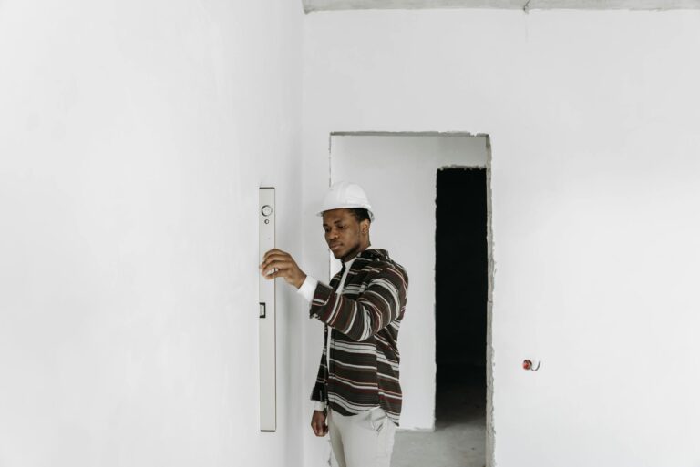 Architect wearing hard hat checks wall alignment in a renovation project.